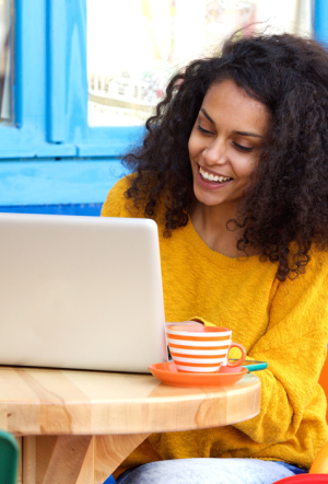 Person looking at a laptop while drinking coffee